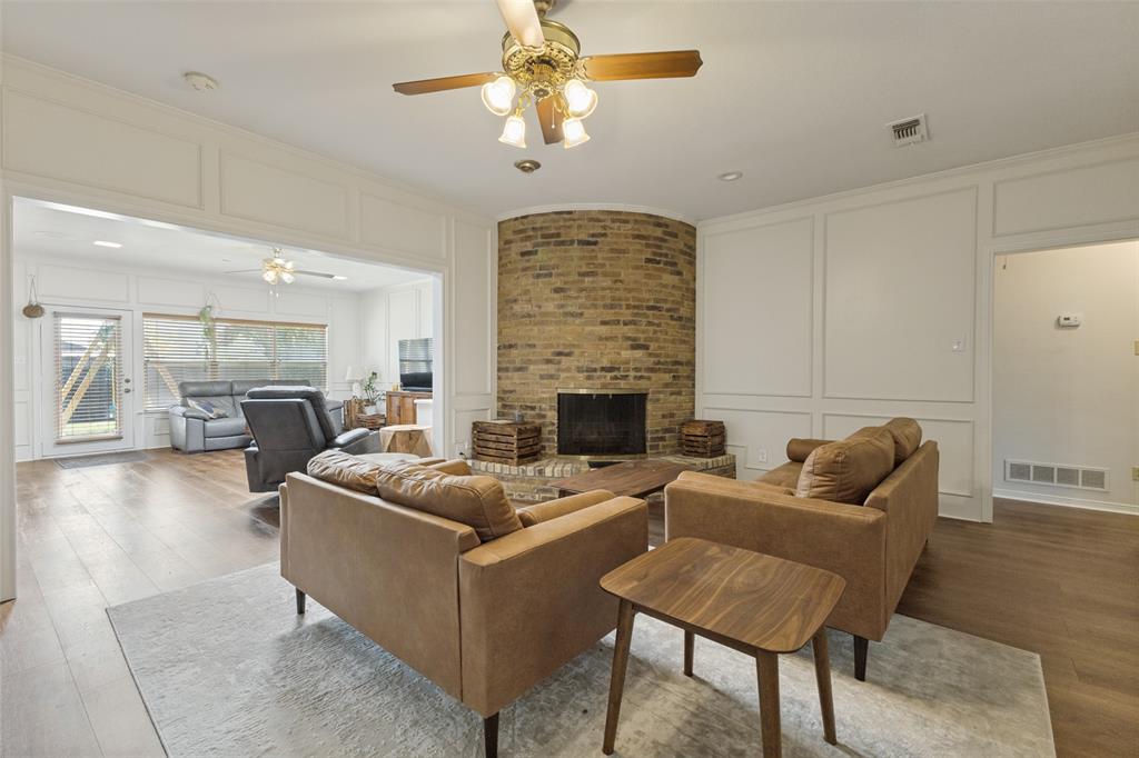 705 South Grove Road Richardson, TX 75081 - Photo 5 of 26 Living area featuring a brick fireplace, wood-finish flooring, white paneled walls, and a recessed lighting