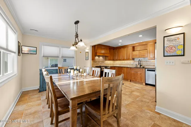 a dining room with stainless steel appliances kitchen island granite countertop a table chairs and a refrigerator