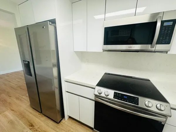 a view of kitchen with stainless steel appliances and refrigerator