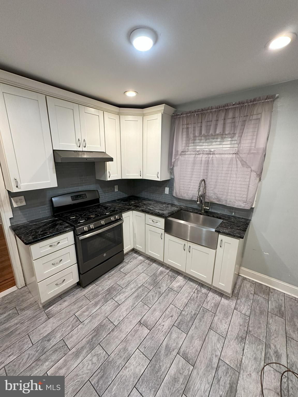 1126 Sanger Street Philadelphia, PA 19124 - Photo 7 of 21 a kitchen with granite countertop a stove a sink and a microwave