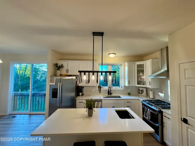 a kitchen with kitchen island a large counter top space a sink stainless steel appliances and cabinets