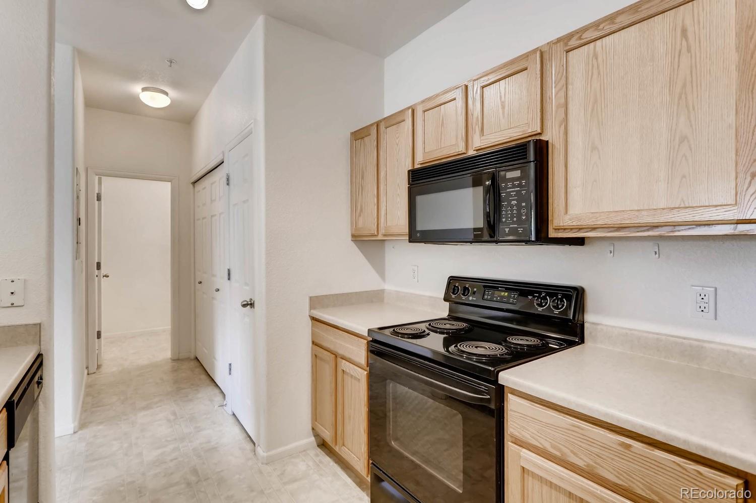 5255 Memphis Street, Unit 811 Denver, CO 80239 - Photo 7 of 12 a kitchen with stainless steel appliances granite countertop white cabinets and a stove top oven