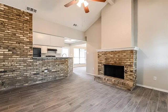 a view of an empty room with wooden floor fireplace and a window