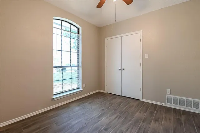 an empty room with wooden floor cabinet and windows