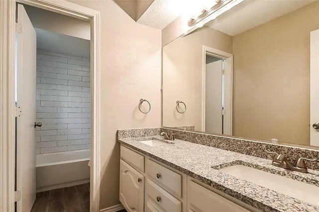 a bathroom with a granite countertop sink a mirror and a bathtub
