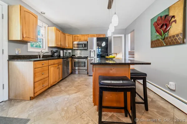 a kitchen with stainless steel appliances granite countertop a stove top oven a sink a dining table and chairs with wooden floor