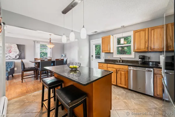 a kitchen with stainless steel appliances granite countertop wooden cabinets a dining table and chairs