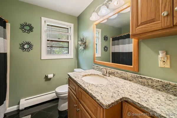 a bathroom with a granite countertop sink a mirror and a toilet