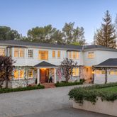 a view of a white house with large windows and a small yard
