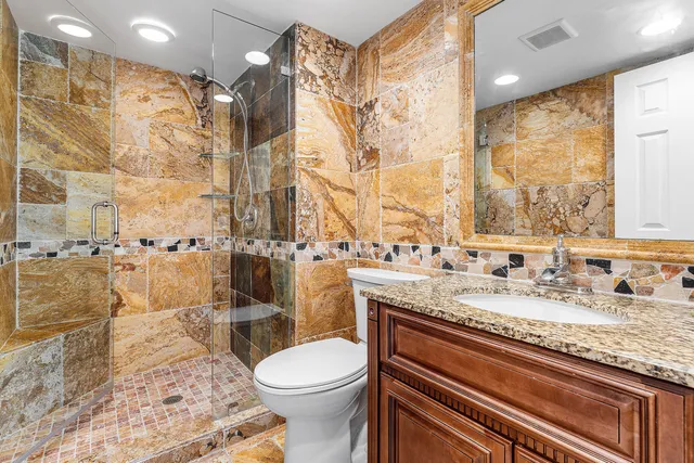 a bathroom with a granite countertop sink toilet and shower