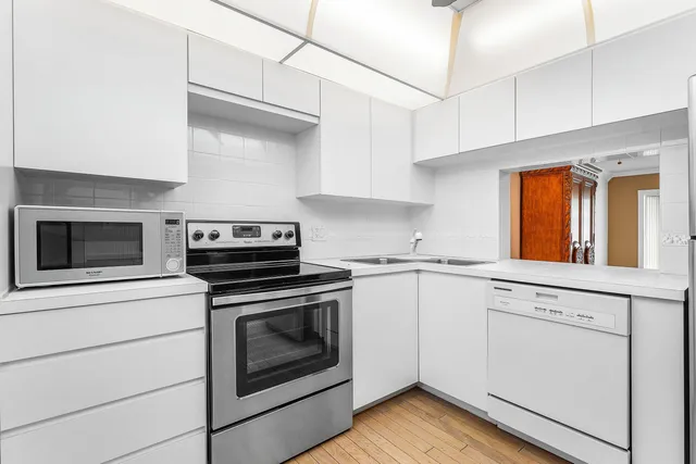a kitchen with cabinets stainless steel appliances and wooden floor