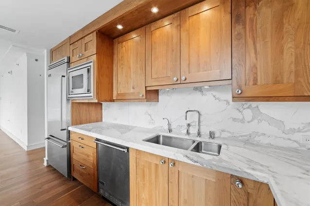 a kitchen with stainless steel appliances granite countertop a sink a stove and a microwave with wooden floor