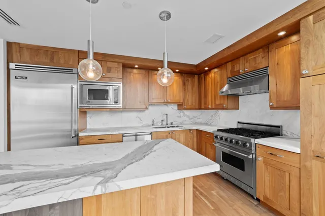 a kitchen with stainless steel appliances granite countertop a sink a stove and a wooden floors