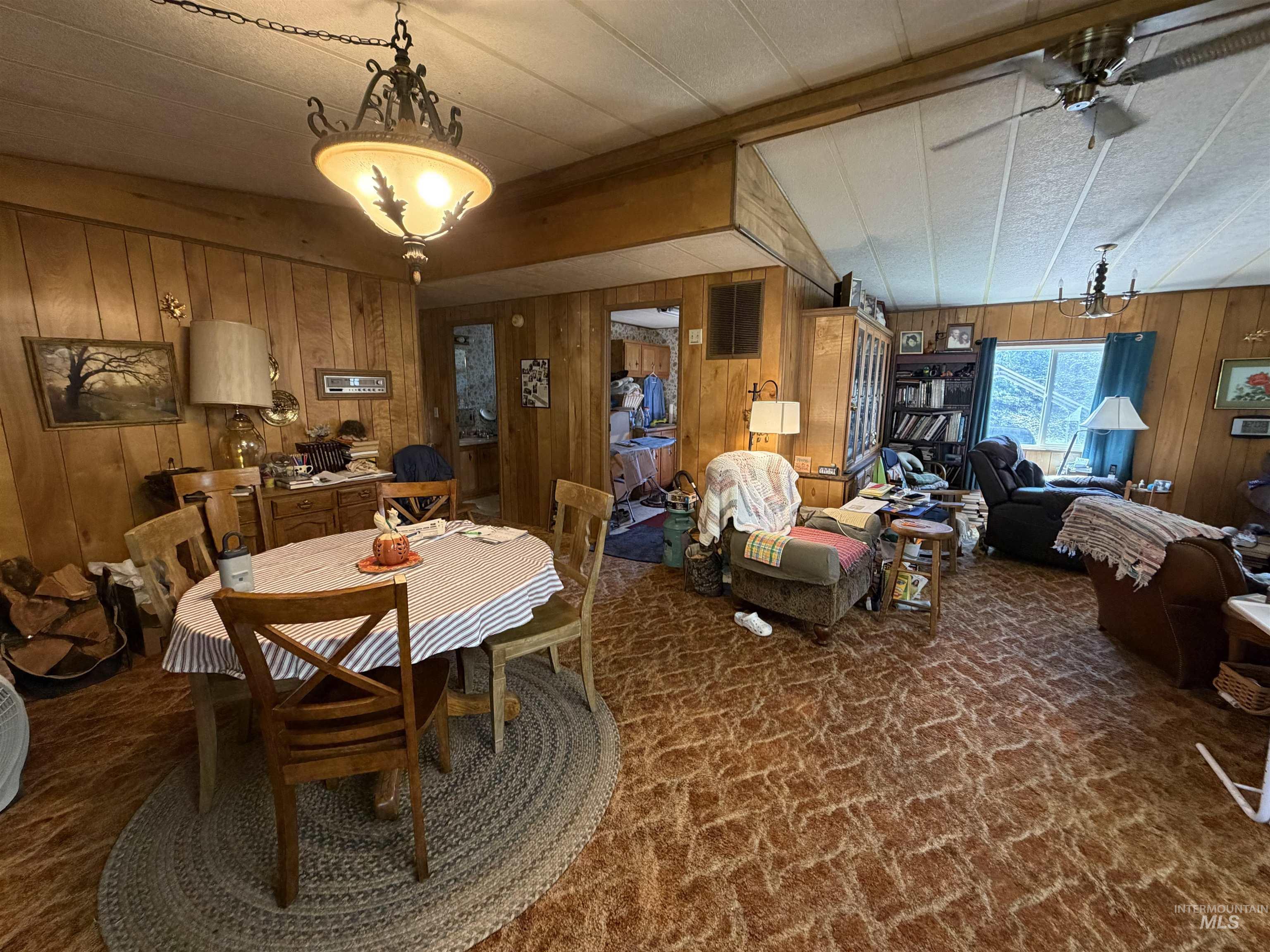 27474 North Tom Beall Road Lapwai, ID 83540 - Photo 38 of 50 Dining room with wood walls, dark carpet, hanging lights, and ceiling fan