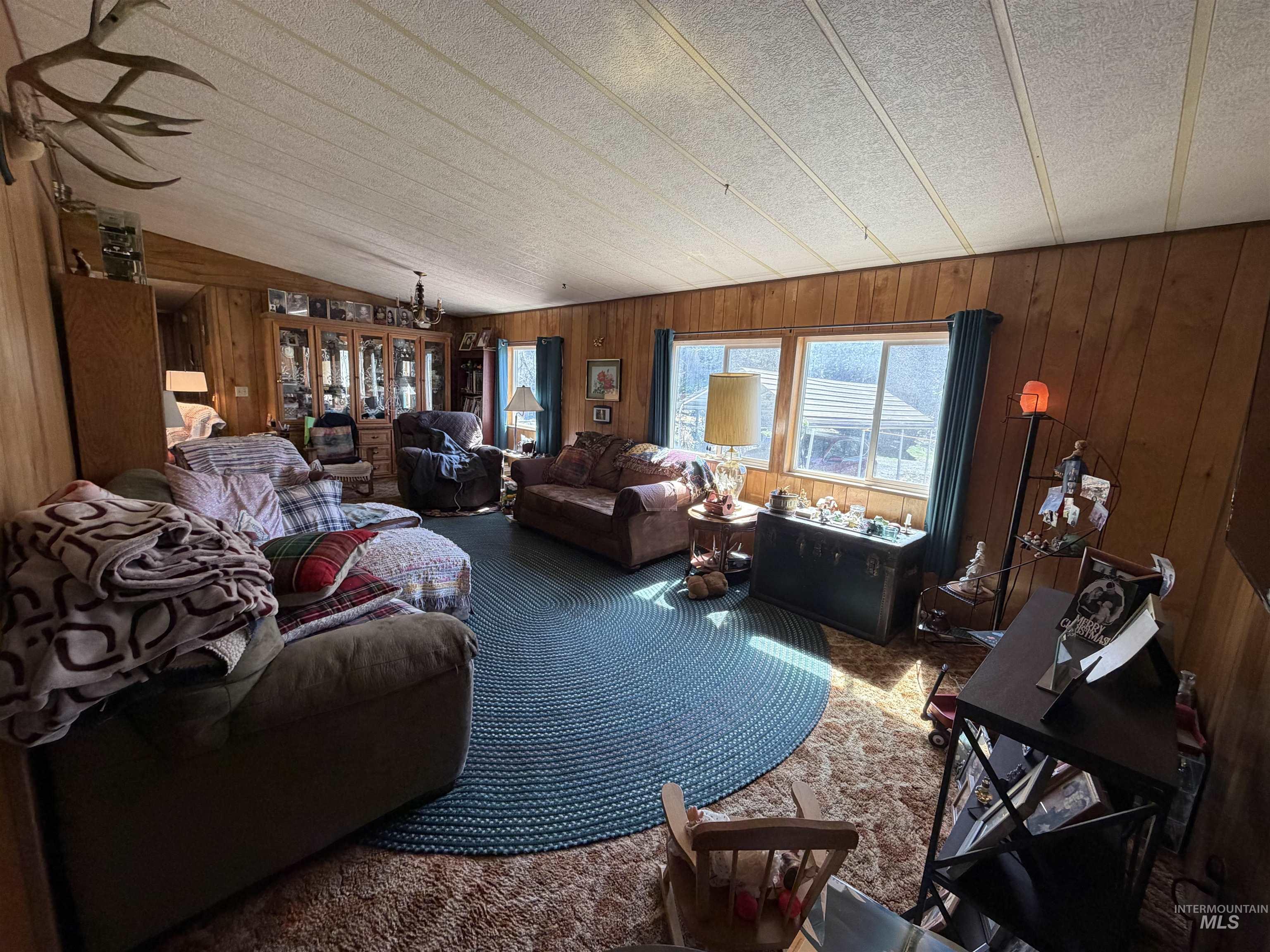 27474 North Tom Beall Road Lapwai, ID 83540 - Photo 46 of 50 Carpeted living room with wooden walls, suspended lighting, and vaulted ceiling