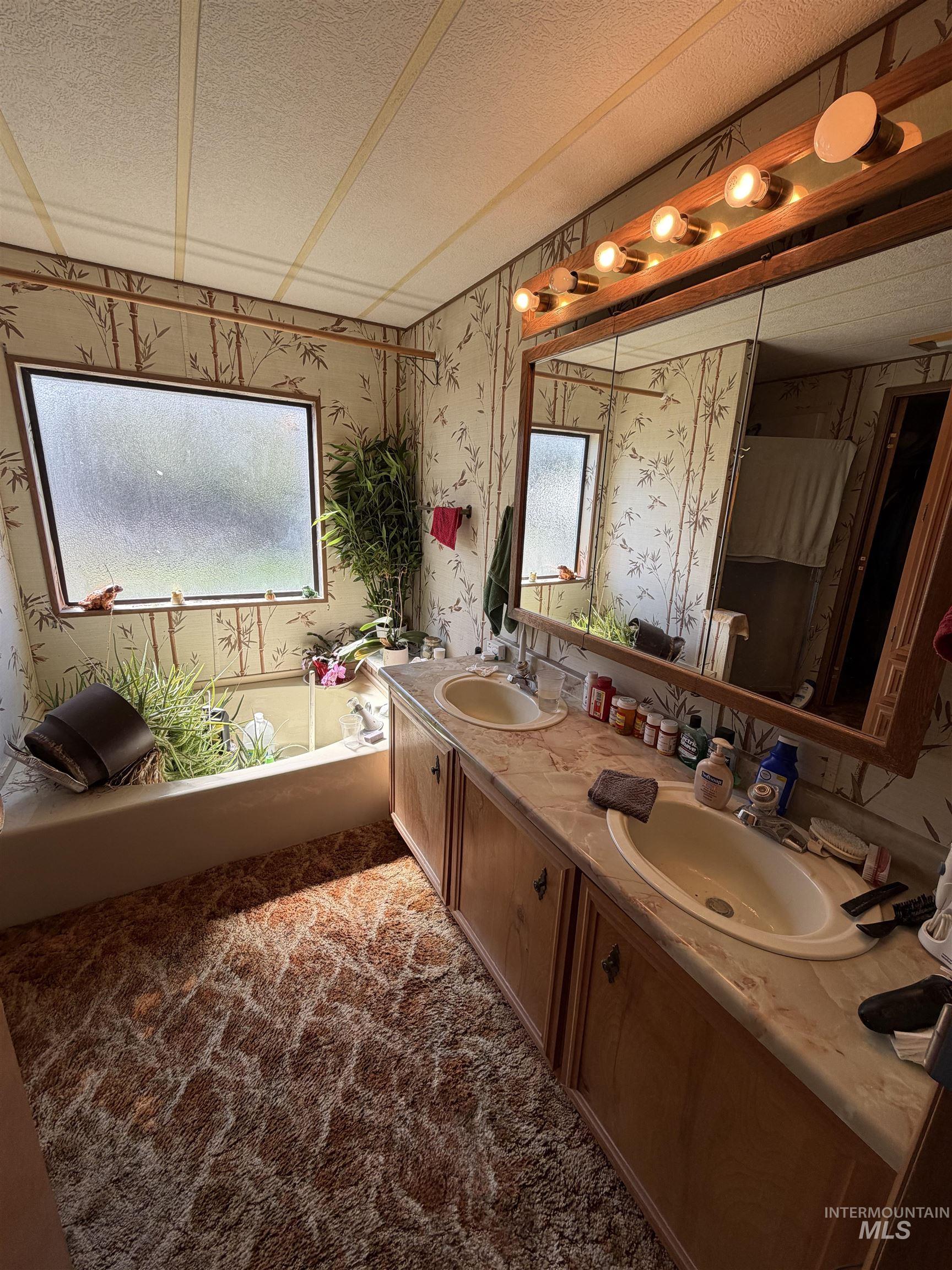 27474 North Tom Beall Road Lapwai, ID 83540 - Photo 50 of 50 Full bathroom featuring double vanity, a textured ceiling, wallpapered walls, a bath, and dark carpet