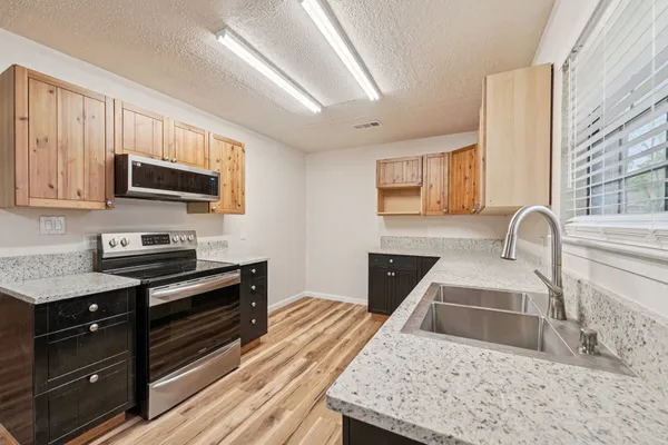a kitchen with stainless steel appliances granite countertop a stove a sink and a microwave