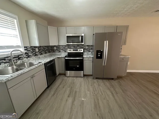 a kitchen with a sink wooden floor and stainless steel appliances