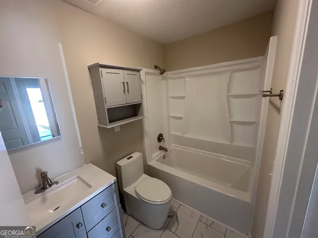 a bathroom with a granite countertop toilet sink and shower