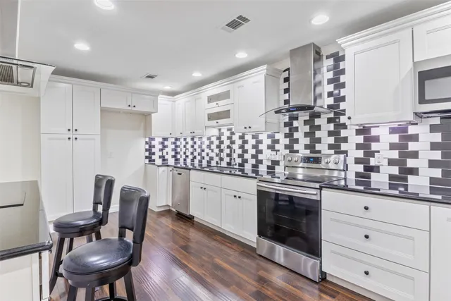 a kitchen with granite countertop white cabinets stainless steel appliances and dining table