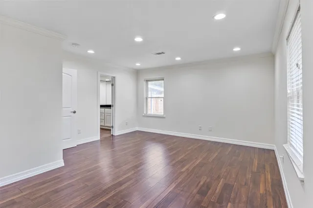 a view of an empty room with wooden floor and window