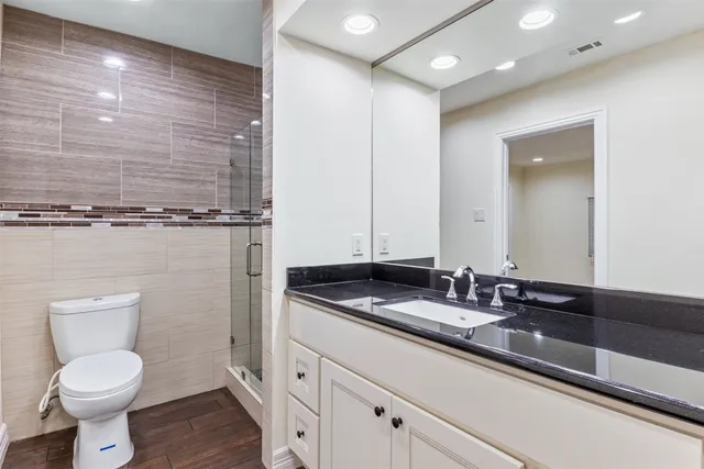 a bathroom with a granite countertop sink a toilet a mirror and shower