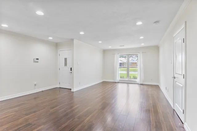 a view of an empty room with wooden floor and window
