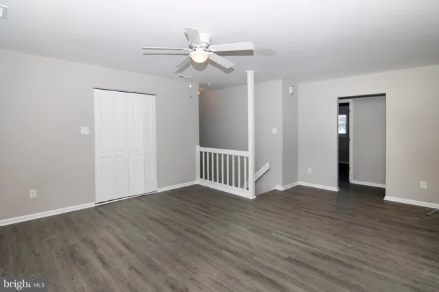 an empty room with wooden floor fan and windows