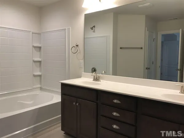 a bathroom with a tub sink and mirror
