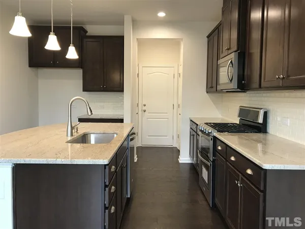 a kitchen with stainless steel appliances granite countertop a sink a stove and a refrigerator