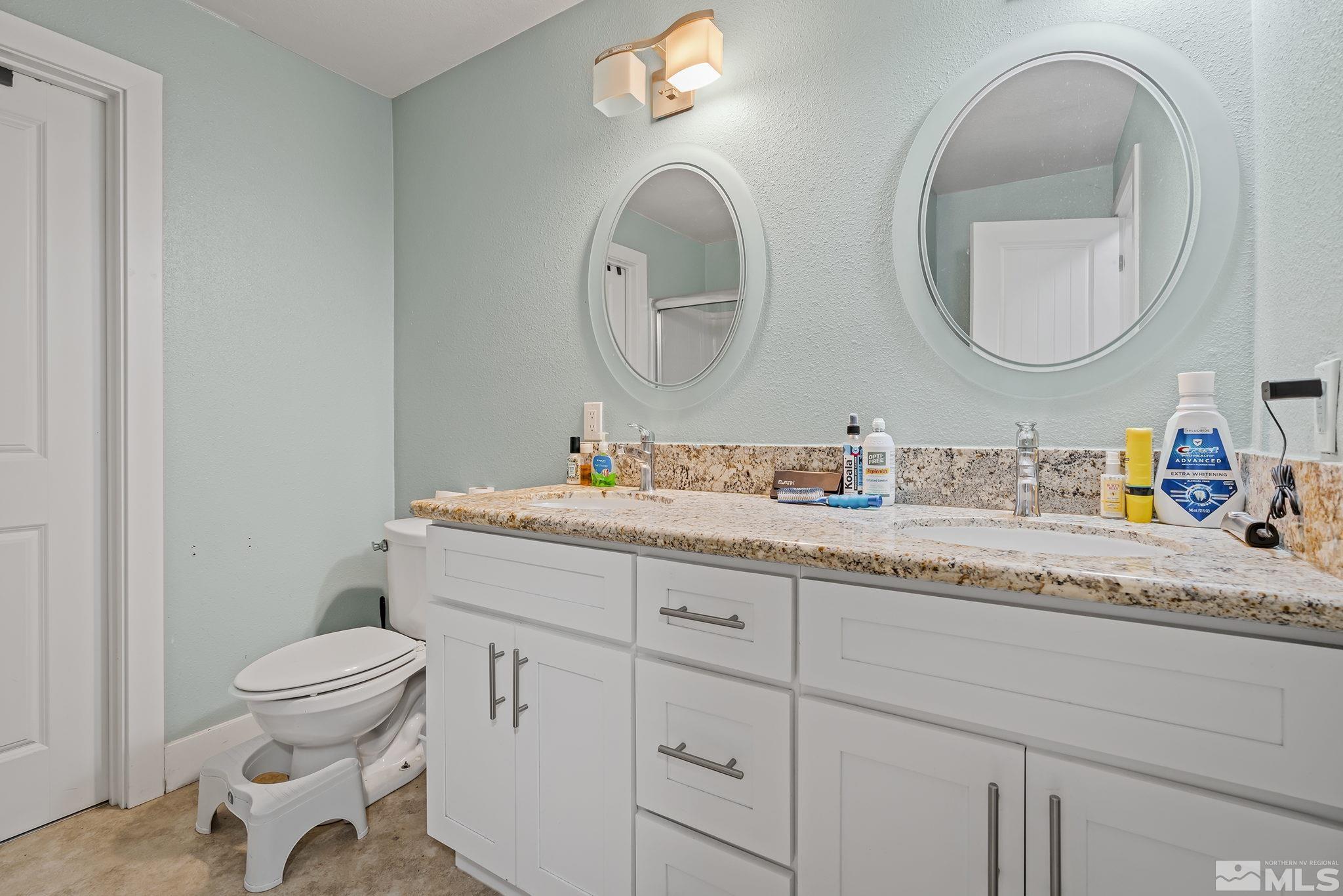 1001 Nevada Street Reno, NV 89503 - Photo 11 of 16 a bathroom with a granite countertop toilet a sink and a mirror