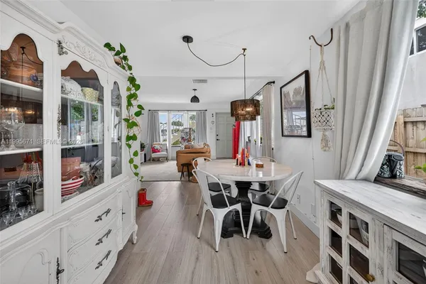 a view of a dining room and livingroom with furniture wooden floor a rug a flat screen tv a painting and a chandelier