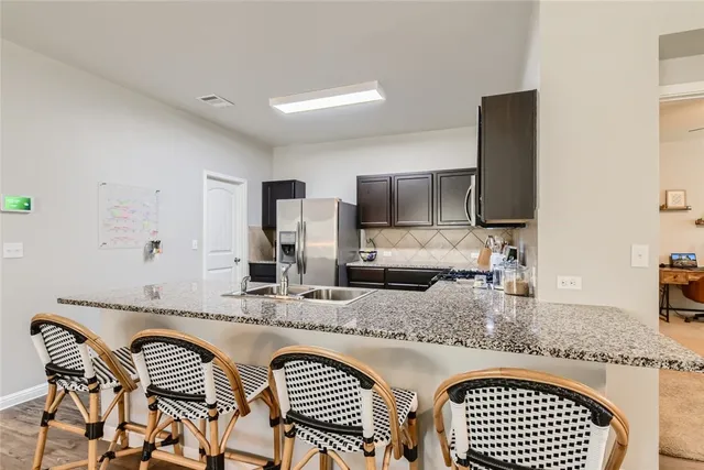 a kitchen with granite countertop stainless steel appliances a sink and a counter top space