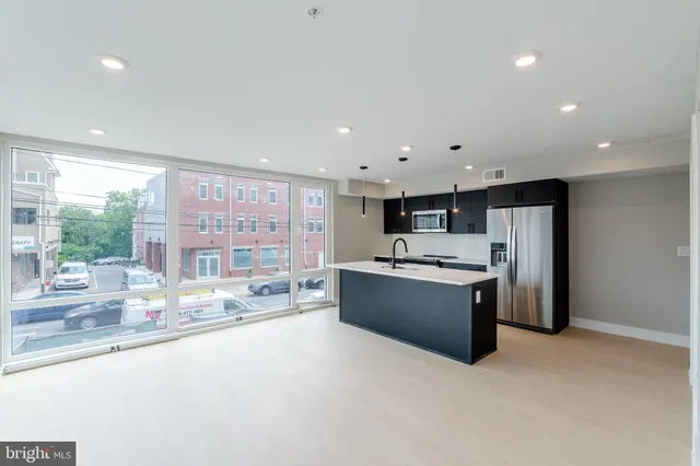 a large kitchen with stainless steel appliances a large counter top and a large window