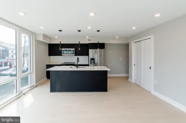 a large kitchen with stainless steel appliances kitchen island granite countertop a refrigerator a sink a stove and a cabinets