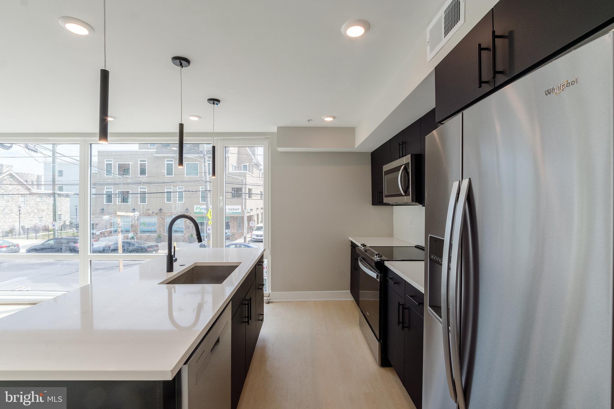 6604 Ridge Avenue, Unit 205 Philadelphia, PA 19128 - Photo 9 of 22 a kitchen with kitchen island granite countertop a sink stainless steel appliances and cabinets