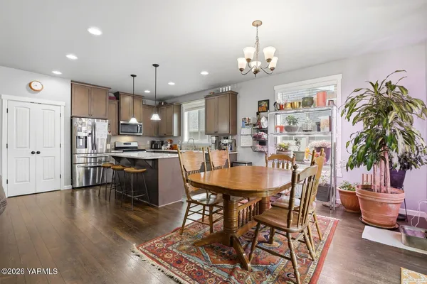 a view of a dining room and livingroom with furniture wooden floor a rug a fireplace and a chandelier