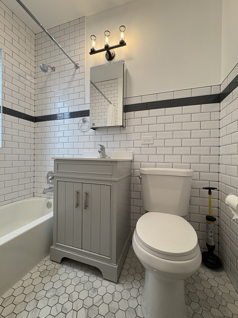 3245 Wisconsin Avenue, Unit 1S Berwyn, IL 60402 - Photo 3 of 10 a bathroom with a toilet a sink a mirror and bathtub