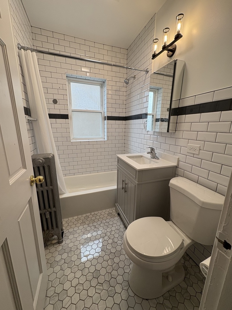3245 Wisconsin Avenue, Unit 1S Berwyn, IL 60402 - Photo 4 of 10 a bathroom with a sink a toilet a mirror and shower