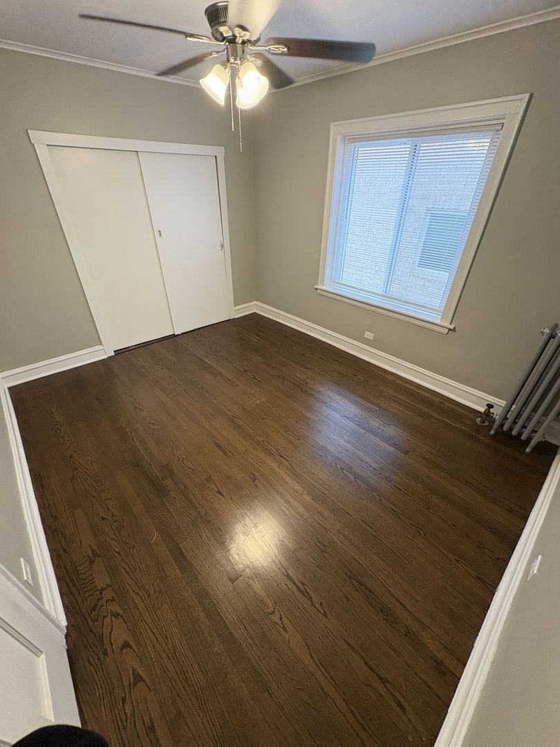 3245 Wisconsin Avenue, Unit 1S Berwyn, IL 60402 - Photo 5 of 10 an empty room with wooden floor fan and windows