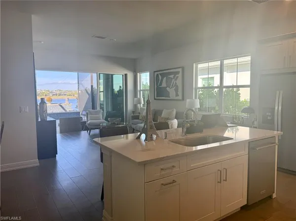 a dining hall with stainless steel appliances granite countertop a sink a stove and a wooden floors
