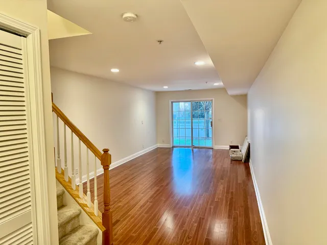 a view of an empty room with wooden floor and stairs