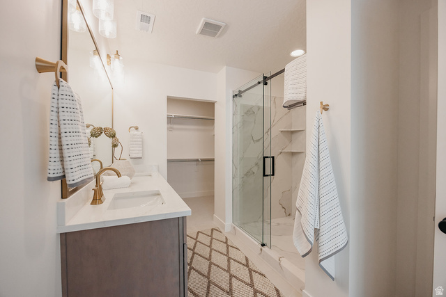 5902 Canyon Rim Road, Unit 620 Lehi, UT 84048 - Photo 45 of 78 Bathroom featuring a dual-sink vanity with a light countertop, gold-finish fixtures, and a shower with a sliding glass door
