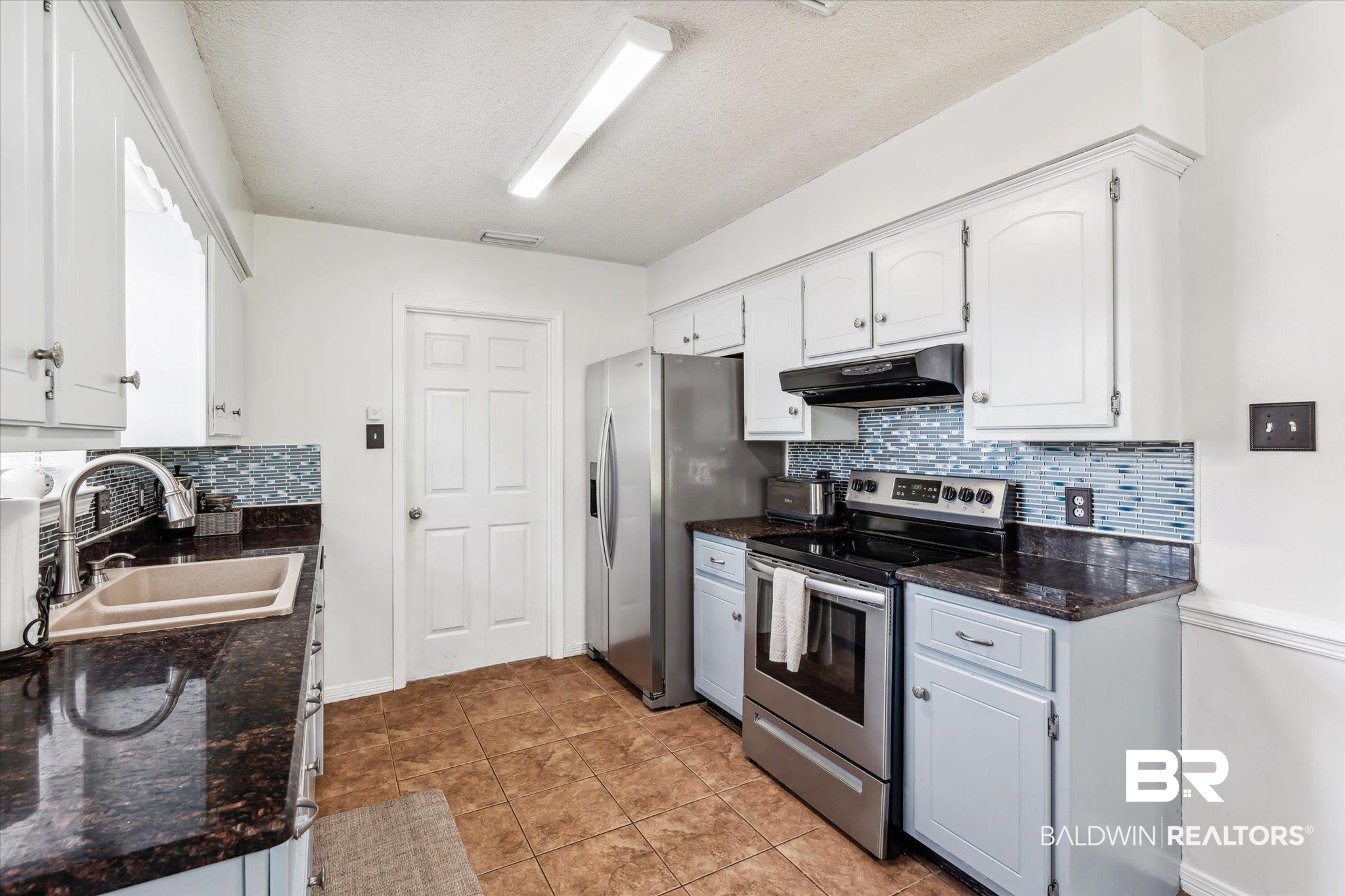 9306 Prairie Drive Semmes, AL 36575 - Photo 7 of 20 Kitchen featuring dark stone counters, stainless steel appliances, decorative backsplash, sink, and light tile patterned floors