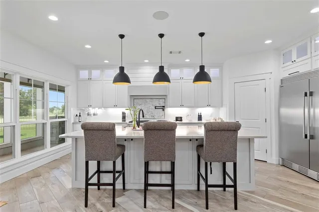 a kitchen with stainless steel appliances kitchen island granite countertop a table chairs and a refrigerator