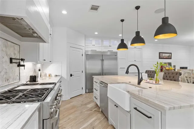 a kitchen with kitchen island stainless steel appliances a sink a stove and a wooden floors