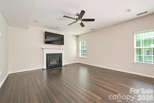 an empty room with wooden floor a ceiling fan and windows