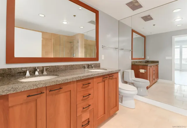 a bathroom with a granite countertop sink mirror vanity and toilet