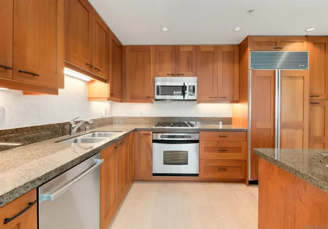 a kitchen with stainless steel appliances granite countertop a stove a sink and a microwave