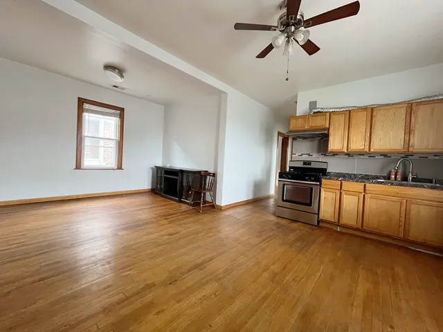 a kitchen with granite countertop a stove a sink and white cabinets with wooden floor next to windows